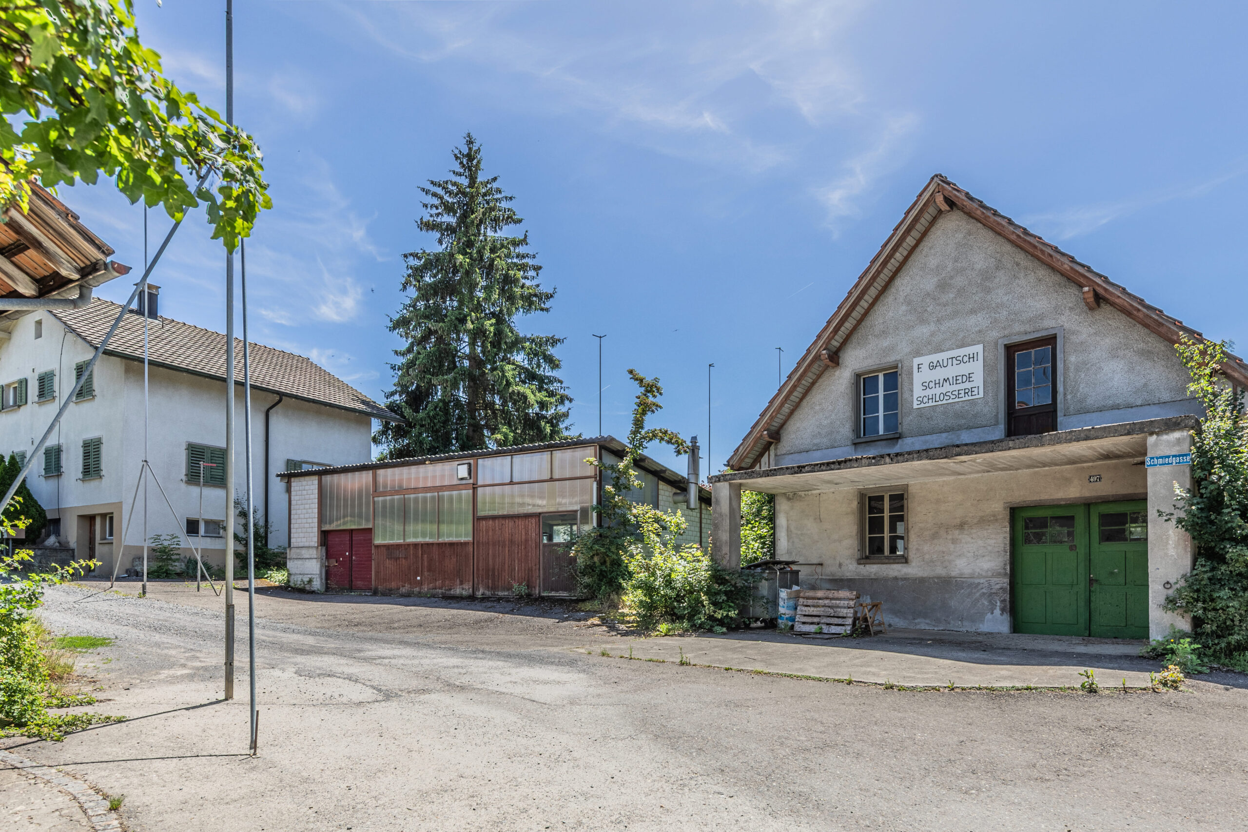 Bauprofile auf einem Grundstück an der Turnhallenstrasse in Gontenschwil markieren die Dimensionen eines geplanten Neubauprojekts. Die freie Grünfläche liegt am Siedlungsrand vor einer bewaldeten Hanglandschaft und veranschaulicht die zukünftige bauliche Entwicklung des Areals. Alte Schmiede.