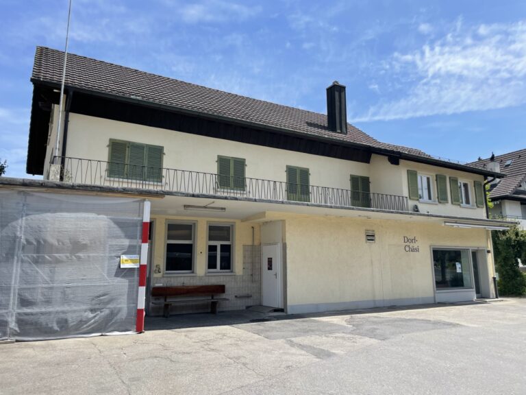 Gebäude der Dorf-Chäsi, alte Käsi, Rickenbach mit heller Fassade, grünen Fensterläden und Balkon im Obergeschoss.